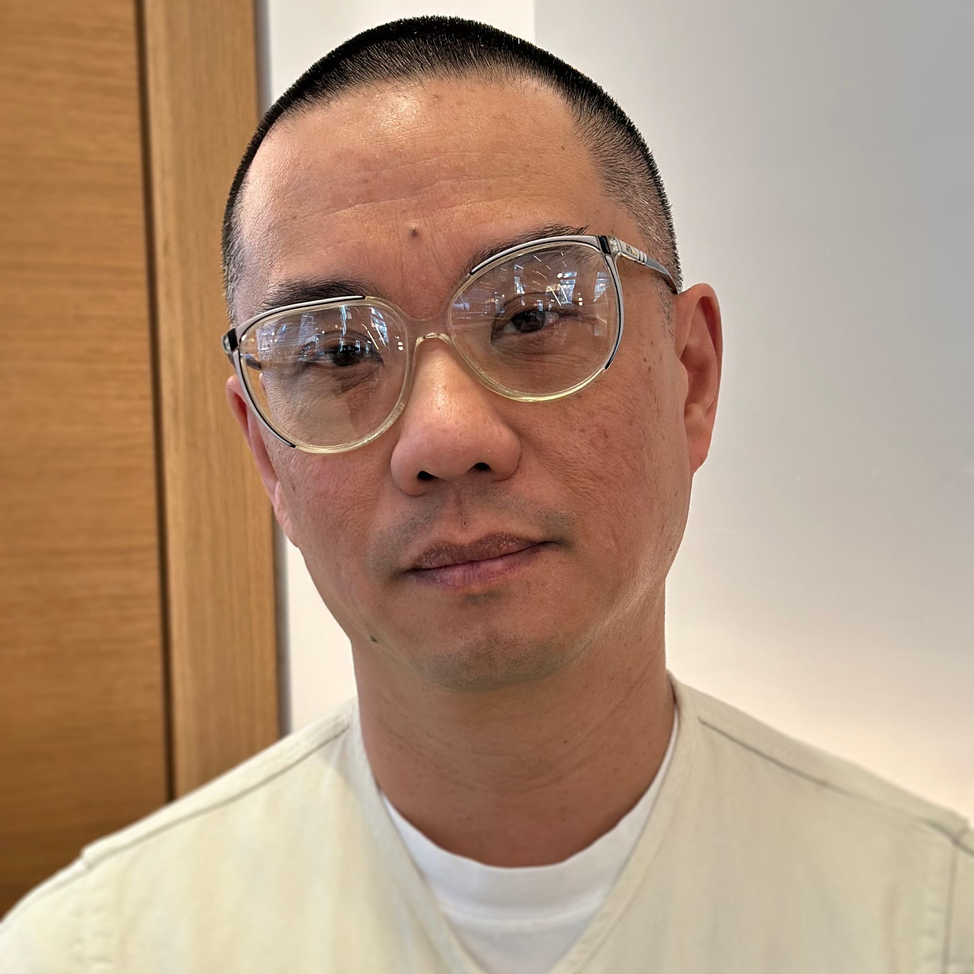 Candid photo graph of Hans wearing light colours in front of a white and light wood background